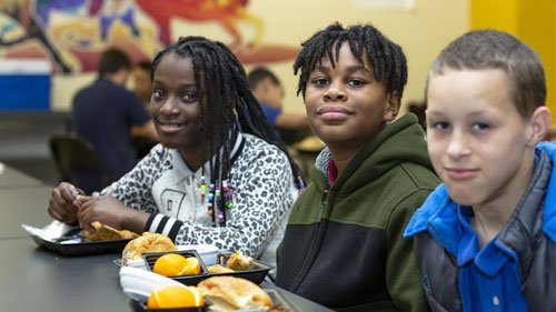 One girl and two boy students eating lunch