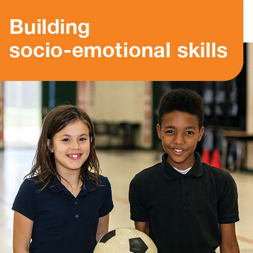 Two young children holding a soccer ball with a text in large font above them stating "Building socio-emotional skills"
